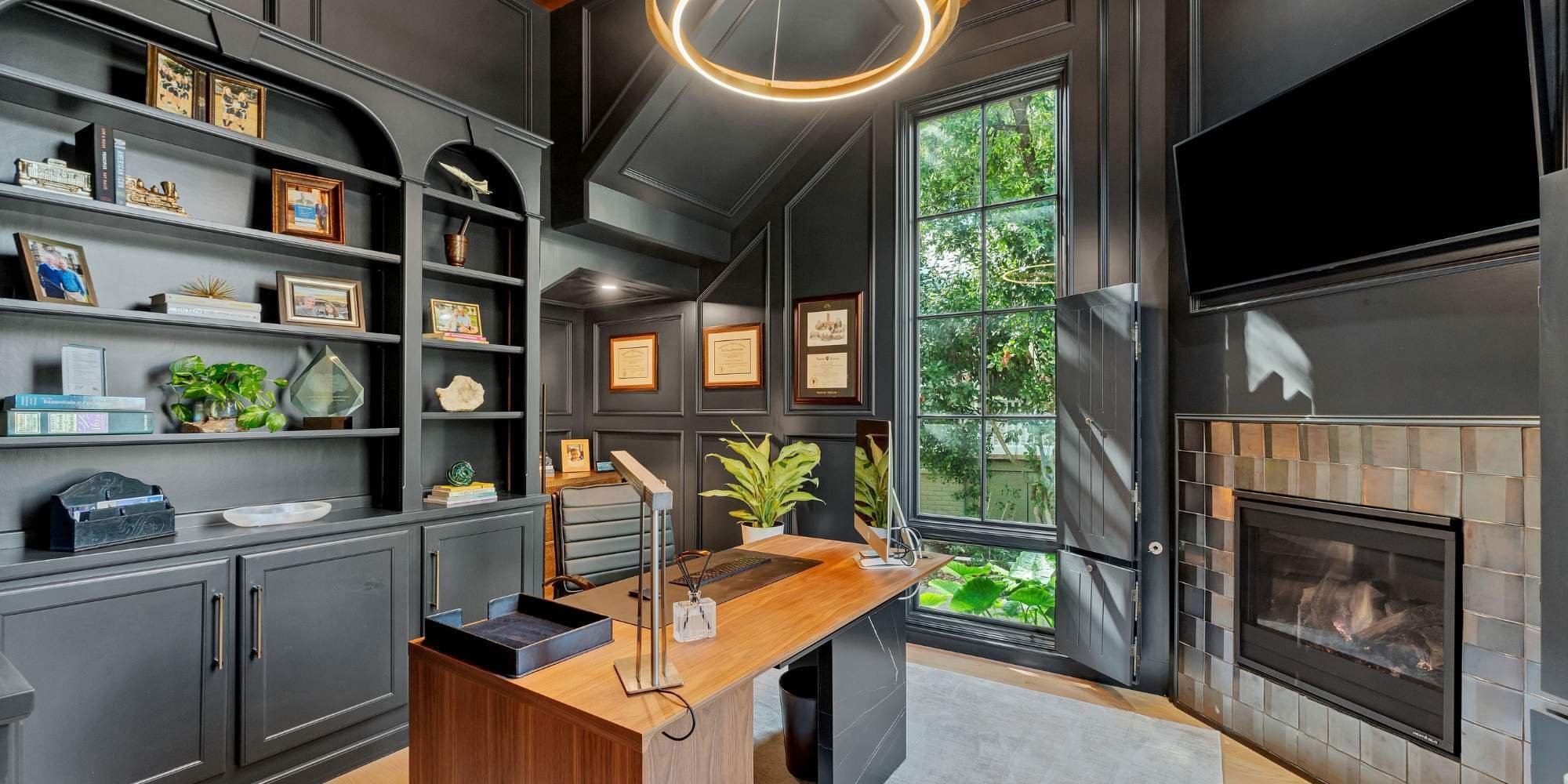 Dark-toned home office with modern desk and fireplace by Hill Haven Homes