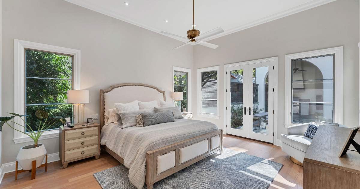 Bedroom in a San Antonio custom home by Hill Haven Homes with natural light, wood flooring, and French doors to a patio.