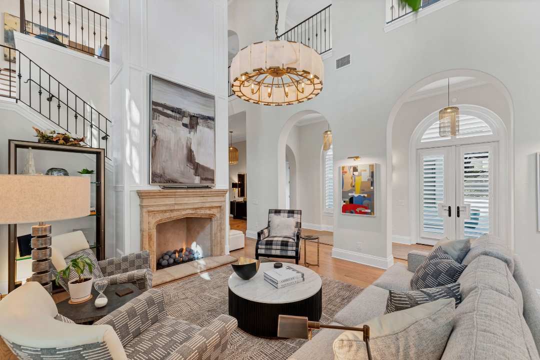 Elegant grand living room with soaring ceilings, modern chandelier, arched doorways, and a central fireplace in San Antonio remodel