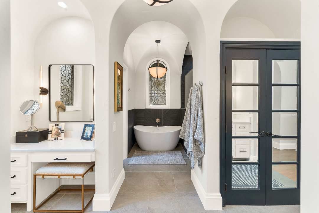 Luxury bathroom remodel with arched ceilings, freestanding tub, makeup vanity, and elegant stained glass window in San Antonio