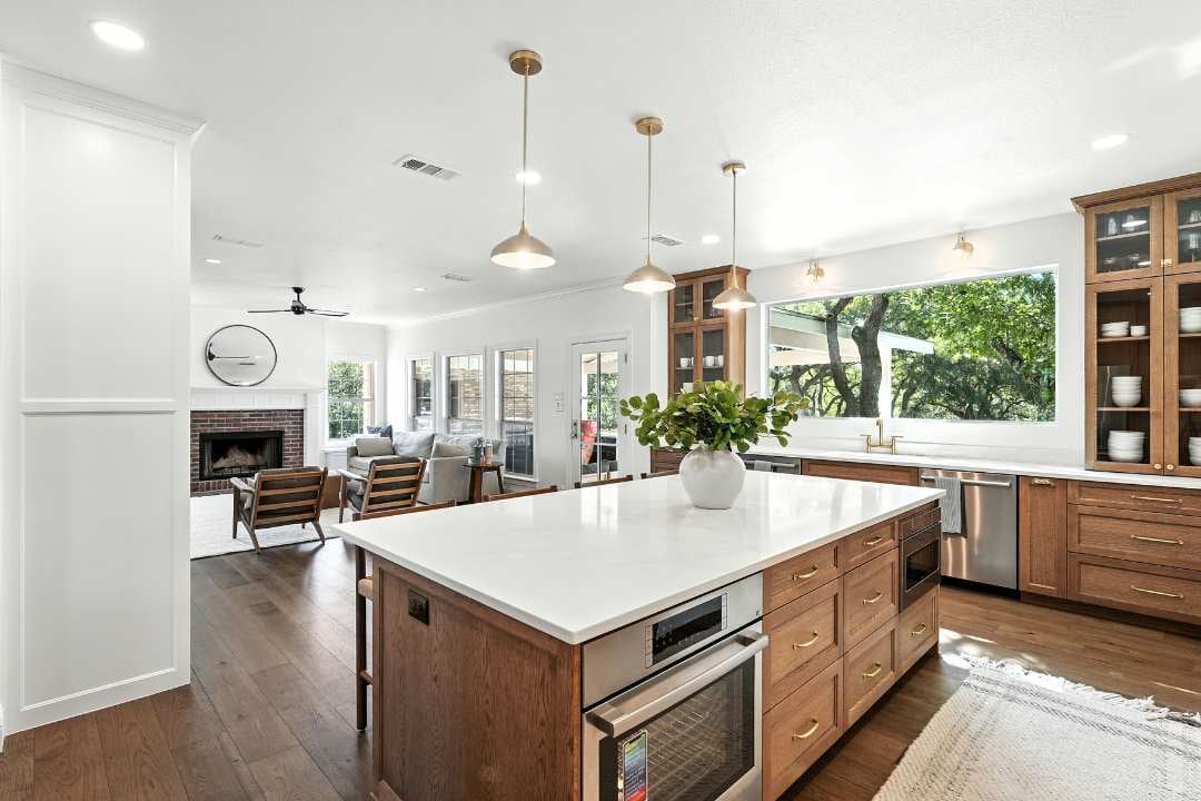 Open-concept kitchen remodel with wood cabinetry, large island, and pendant lights by Hill Haven Homes in San Antonio