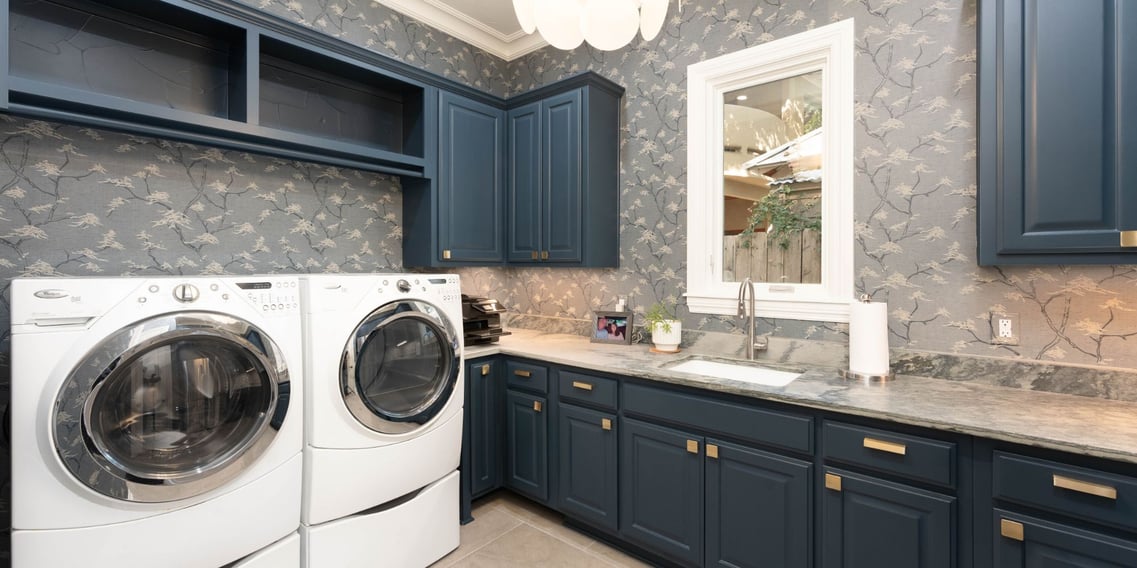 Stylish San Antonio laundry room remodel by Hill Haven Homes featuring navy cabinets and marble countertops